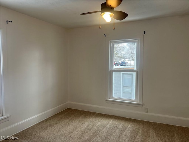 carpeted spare room with baseboards and ceiling fan