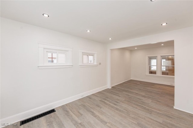 empty room featuring a healthy amount of sunlight, visible vents, baseboards, and wood finished floors