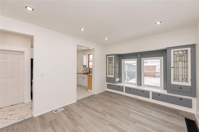 spare room with light wood-type flooring, recessed lighting, visible vents, and a sink