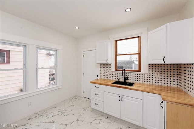 kitchen with tasteful backsplash, a wealth of natural light, marble finish floor, and a sink