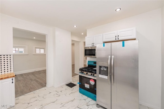 kitchen featuring stainless steel appliances, recessed lighting, marble finish floor, and white cabinetry