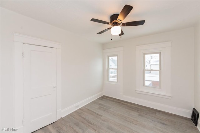 empty room featuring light wood-type flooring, ceiling fan, and baseboards