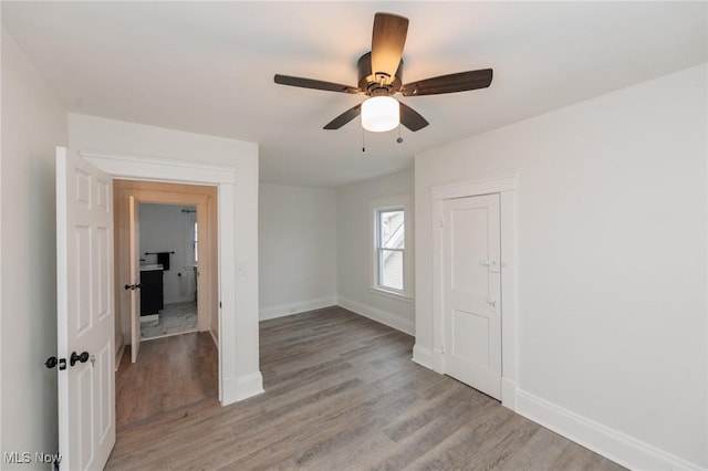 empty room featuring light wood finished floors, baseboards, and a ceiling fan