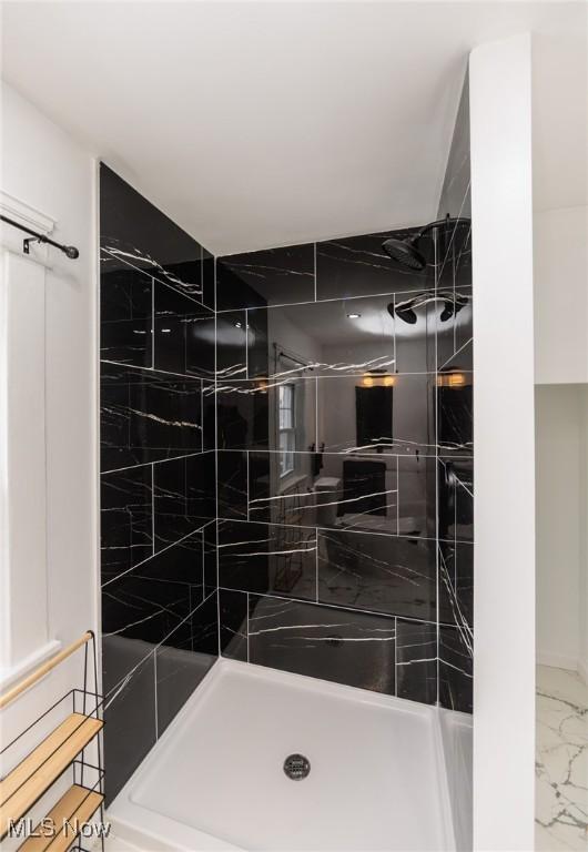 full bath with marble finish floor and a shower stall