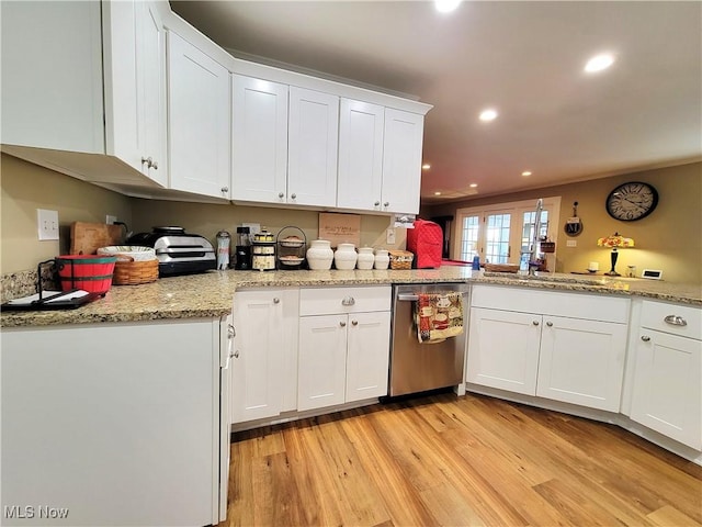 kitchen featuring white cabinets, light wood-type flooring, stainless steel dishwasher, a sink, and recessed lighting