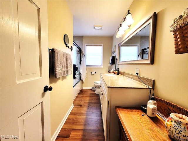 full bathroom featuring toilet, combined bath / shower with glass door, vanity, wood finished floors, and baseboards