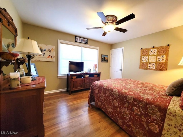 bedroom featuring wood finished floors, a ceiling fan, and baseboards