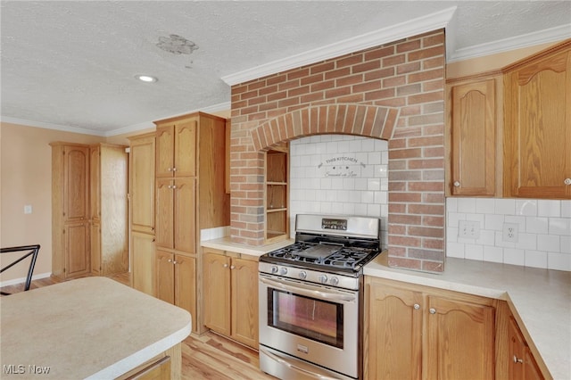kitchen featuring stainless steel range with gas cooktop, light countertops, and crown molding
