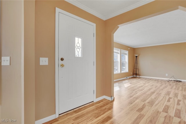 foyer entrance featuring baseboards, light wood finished floors, arched walkways, and crown molding