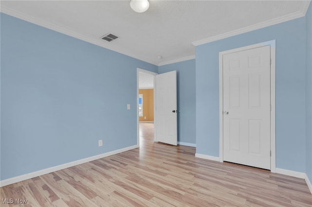 unfurnished bedroom with baseboards, light wood-style flooring, visible vents, and crown molding
