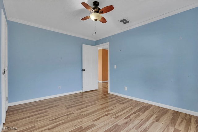 empty room featuring visible vents, crown molding, baseboards, and wood finished floors