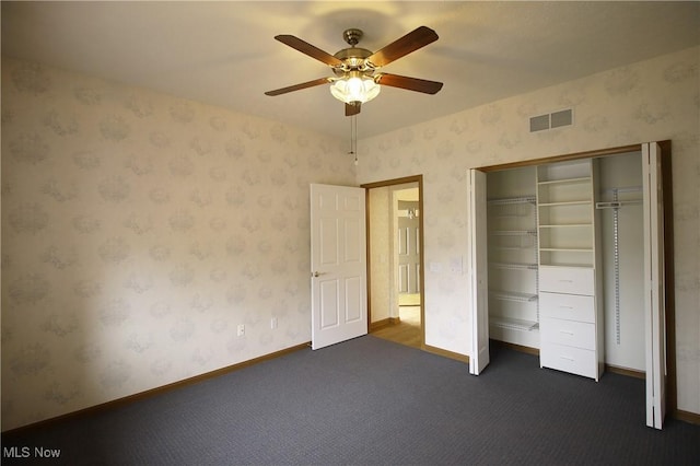 unfurnished bedroom with visible vents, dark carpet, baseboards, and wallpapered walls