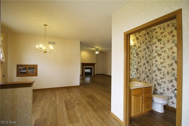 interior space with dark wood-style flooring, a sink, visible vents, and wallpapered walls