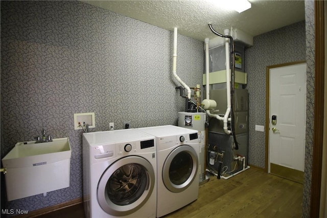 laundry area with laundry area, wood finished floors, a sink, water heater, and washer and clothes dryer