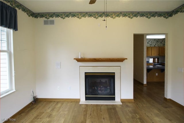 unfurnished living room featuring visible vents, a wealth of natural light, and wood finished floors