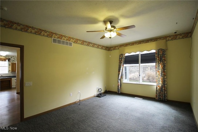 carpeted empty room featuring baseboards, visible vents, and ceiling fan