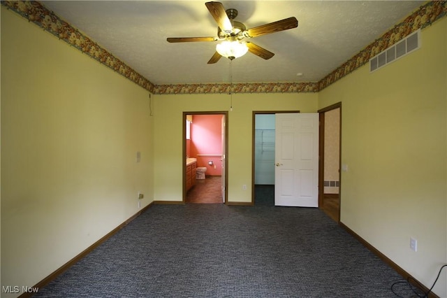 unfurnished bedroom featuring carpet flooring, visible vents, baseboards, a walk in closet, and ensuite bath