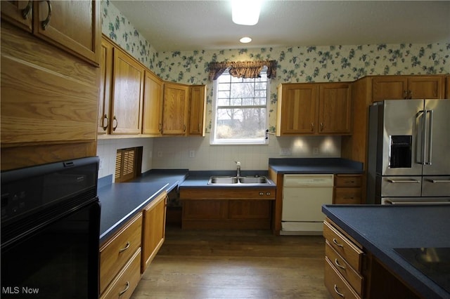 kitchen featuring a sink, black appliances, dark countertops, and wallpapered walls