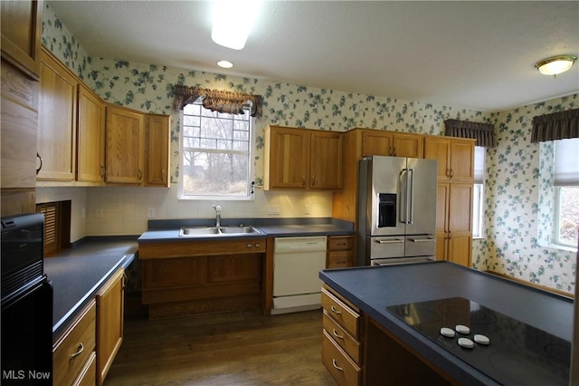 kitchen with wallpapered walls, white dishwasher, a sink, and stainless steel fridge with ice dispenser