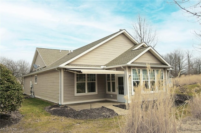 rear view of property with a patio and roof with shingles