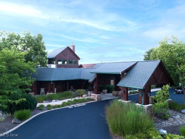 cabin featuring roof with shingles and a chimney