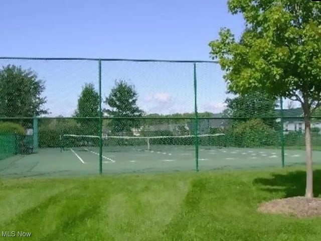 view of property's community with a tennis court and fence