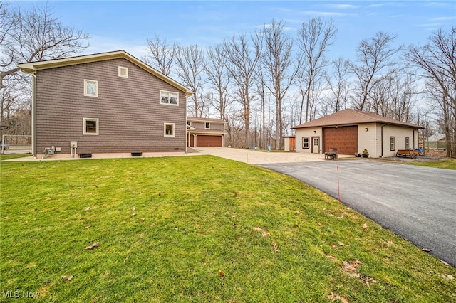 view of side of property featuring a garage, a lawn, and an outbuilding