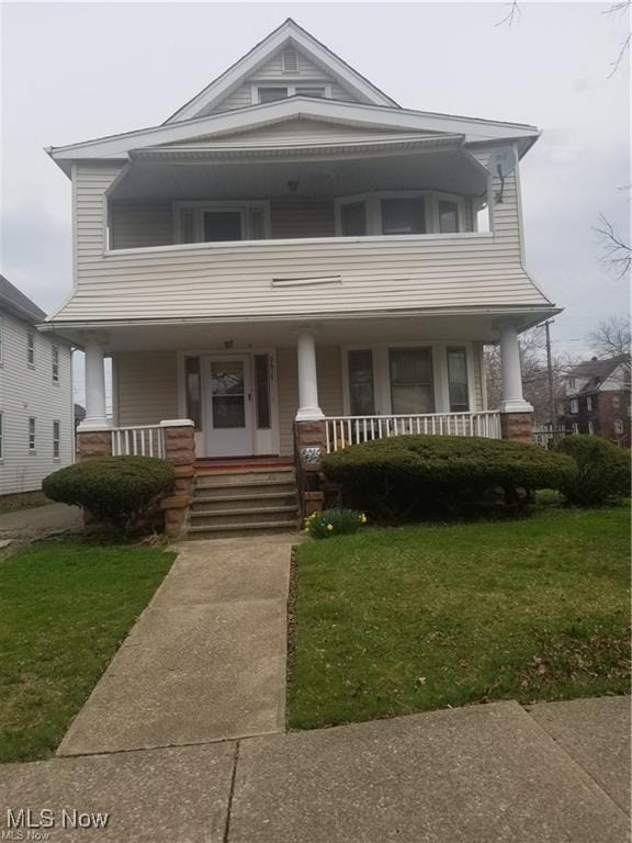 view of front of home with a porch, a balcony, and a front lawn