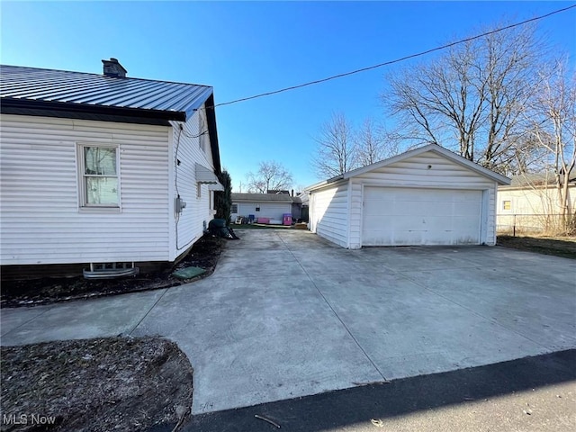 view of side of home featuring a detached garage, a chimney, metal roof, and an outbuilding