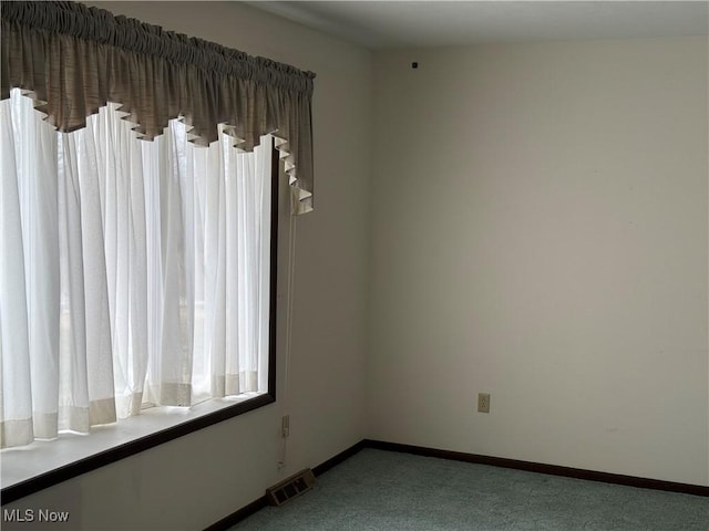 empty room with baseboards, visible vents, and carpet floors