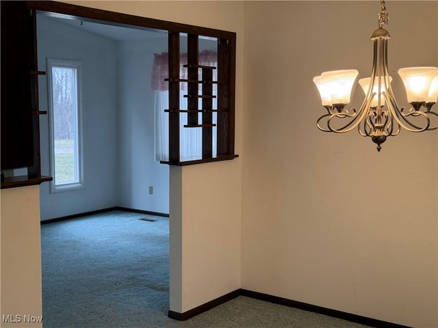 empty room with a notable chandelier, visible vents, baseboards, and carpet