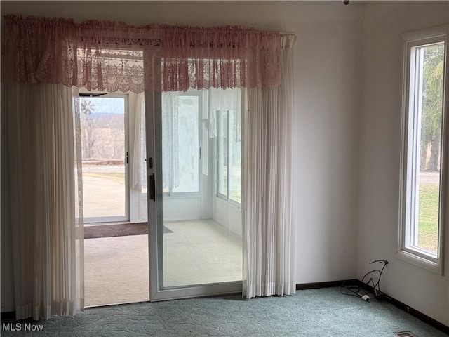 doorway with a wealth of natural light, baseboards, and carpet floors