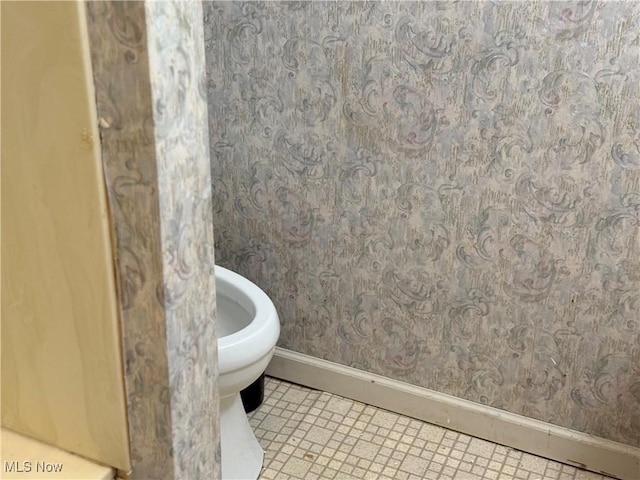 bathroom featuring wallpapered walls, toilet, and baseboards