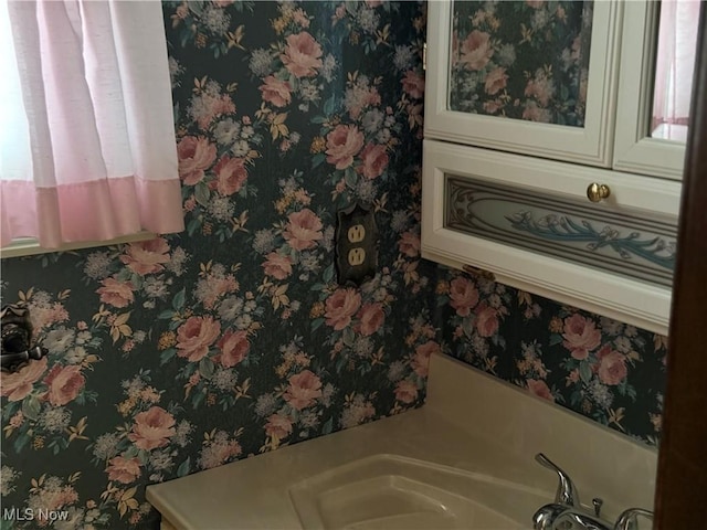 details featuring a bath, wallpapered walls, and a sink