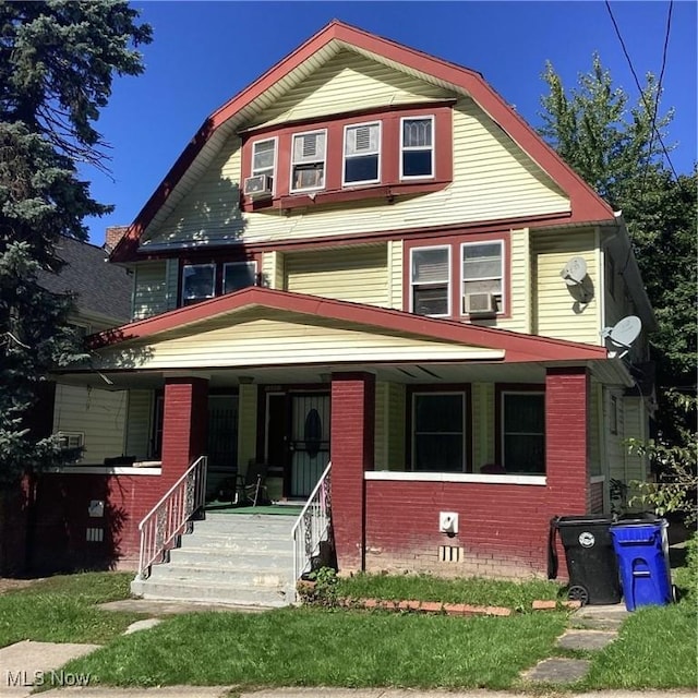 view of front of house with brick siding, a gambrel roof, and a porch