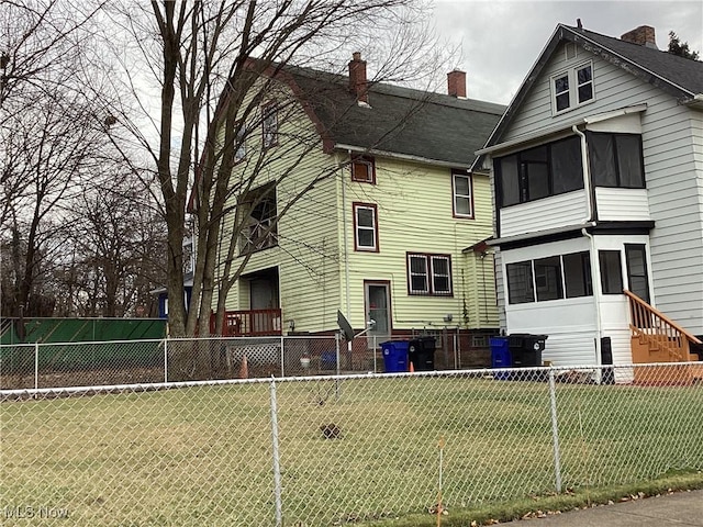 back of property with a lawn, a fenced backyard, and a sunroom