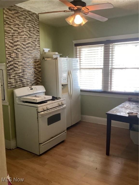 kitchen featuring light wood finished floors, tasteful backsplash, baseboards, ceiling fan, and white appliances