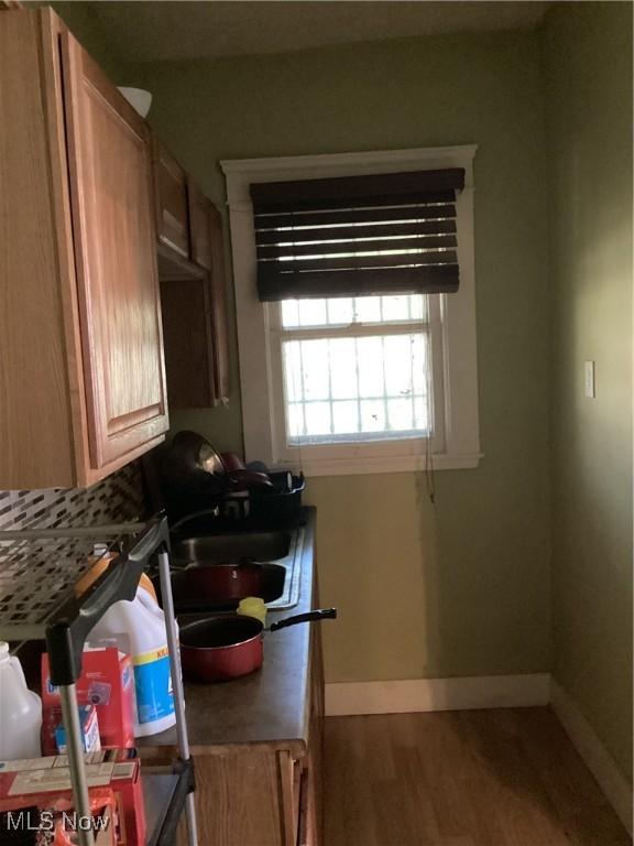 kitchen with decorative backsplash, wood finished floors, baseboards, and a sink