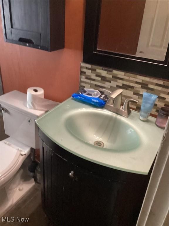 bathroom featuring vanity, toilet, and backsplash