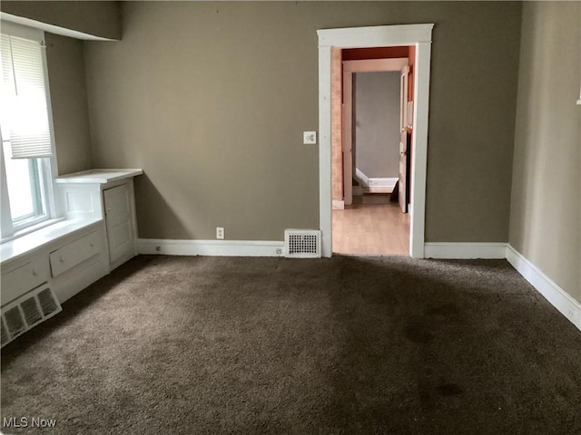 unfurnished room featuring baseboards, visible vents, and dark colored carpet