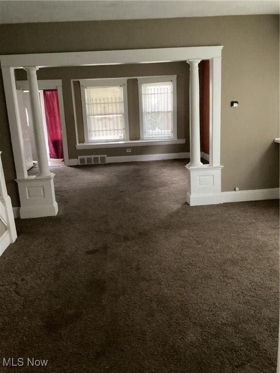 carpeted spare room featuring visible vents, baseboards, and decorative columns