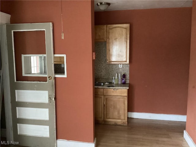 kitchen with wood finished floors, tasteful backsplash, and baseboards