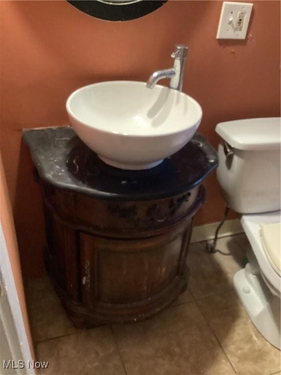 half bath featuring tile patterned flooring, toilet, and vanity