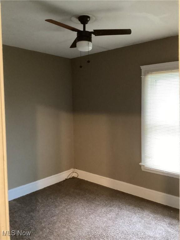 carpeted empty room with a ceiling fan and baseboards