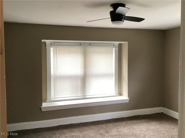 carpeted empty room featuring ceiling fan and baseboards