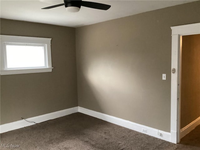 empty room featuring baseboards, dark colored carpet, and ceiling fan