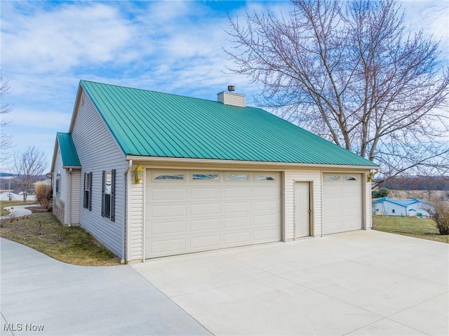 view of home's exterior with metal roof, a garage, and a chimney