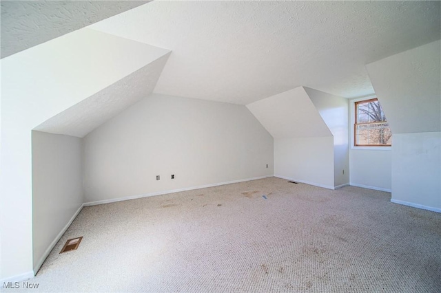 bonus room featuring baseboards, visible vents, lofted ceiling, a textured ceiling, and carpet flooring