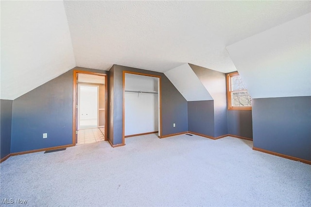 bonus room featuring a textured ceiling, carpet, baseboards, and vaulted ceiling