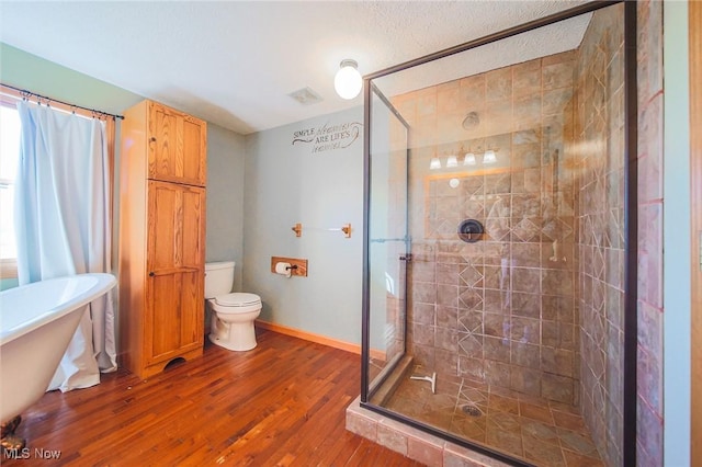 bathroom with toilet, a stall shower, wood finished floors, baseboards, and a soaking tub